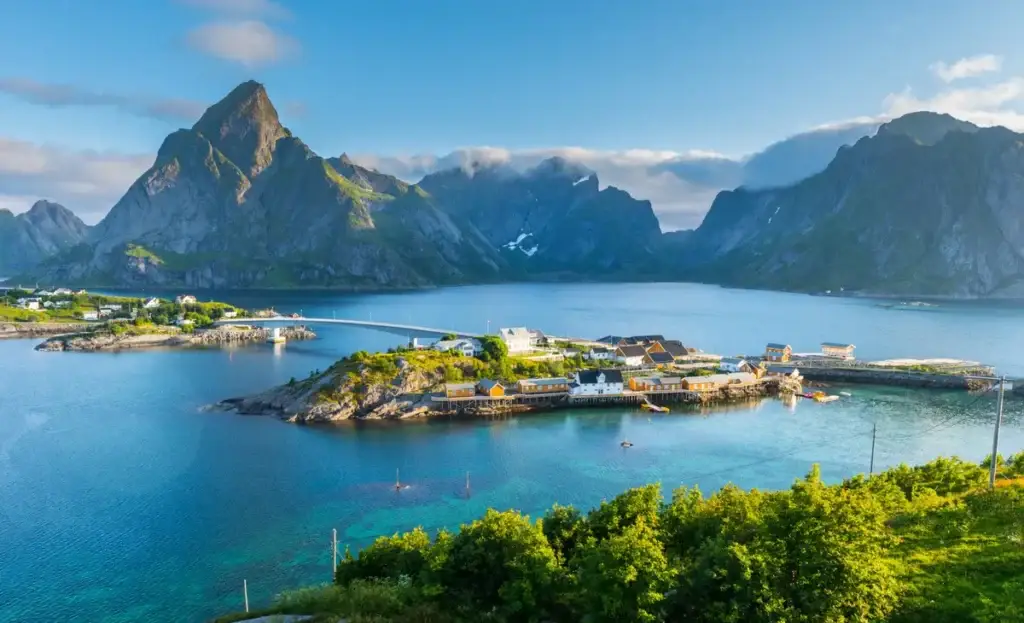 Breathtaking summer view of Lofoten Islands featuring the scenic beauty of mountains, a tranquil sea, and a quaint village in Norway, perfect for adventure and serene getaways.