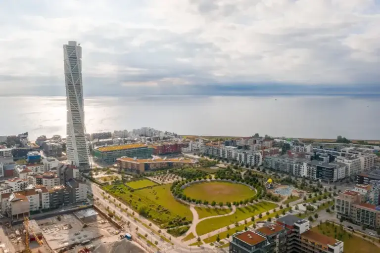 Aerial view of Malmo city in Sweden showcasing the iconic Turning Torso skyscraper and surrounding urban landscape with ocean backdrop.