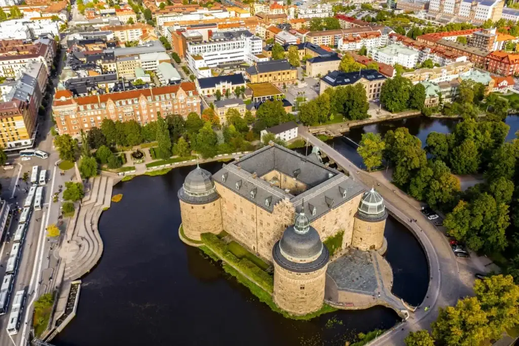 Aerial view of Orebro Castle in Sweden, an historic fortress surrounded by the Svartan River with cityscape in the background, showcasing Scandinavian heritage and architecture.