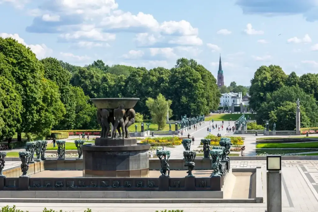 View of the iconic sculptures at Vigeland Park in Oslo, Norway, showcasing an array of bronze statues on a sunny day frequented by visitors.