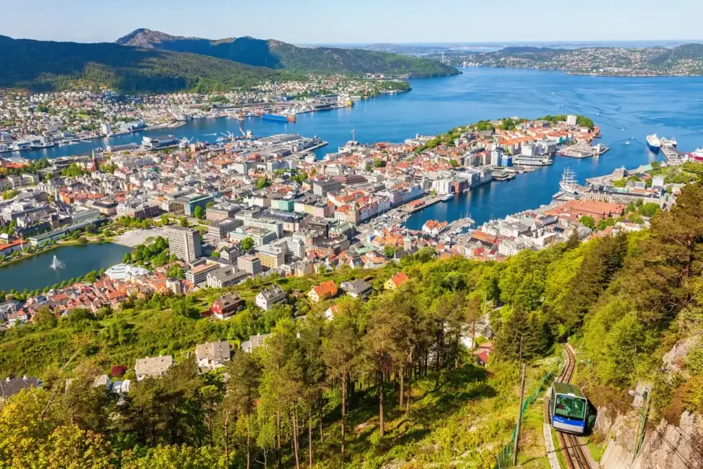 Panoramic view of Bergen city with funicular railway ascending Mount Fløyen, showcasing the vibrant architecture and the surrounding Norwegian fjords.