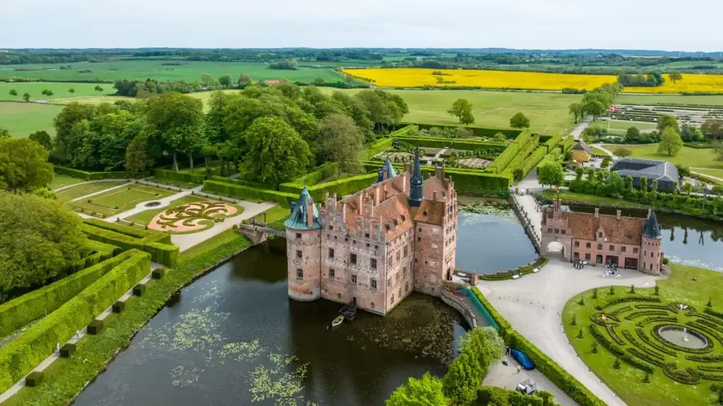 Aerial view of Egeskov Castle and Renaissance Garden in Kværndrup, Denmark, showcasing the intricate garden designs and surrounding lush landscape.