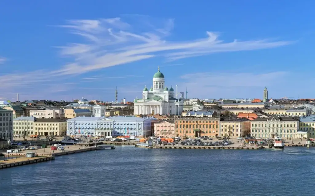 Panoramic view of Helsinki featuring the iconic Helsinki Cathedral, bustling South Harbor, and vibrant Market Square under a blue sky with streaky cirrus clouds, capturing the essence of a sunny spring day in Finland.