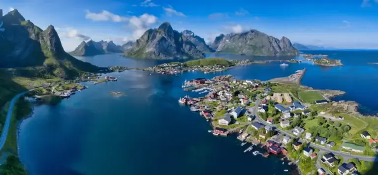 Aerial view of Reine in the Lofoten Islands, Norway, showcasing the dramatic mountain landscapes and picturesque fishing village with its traditional red rorbuer cabins.