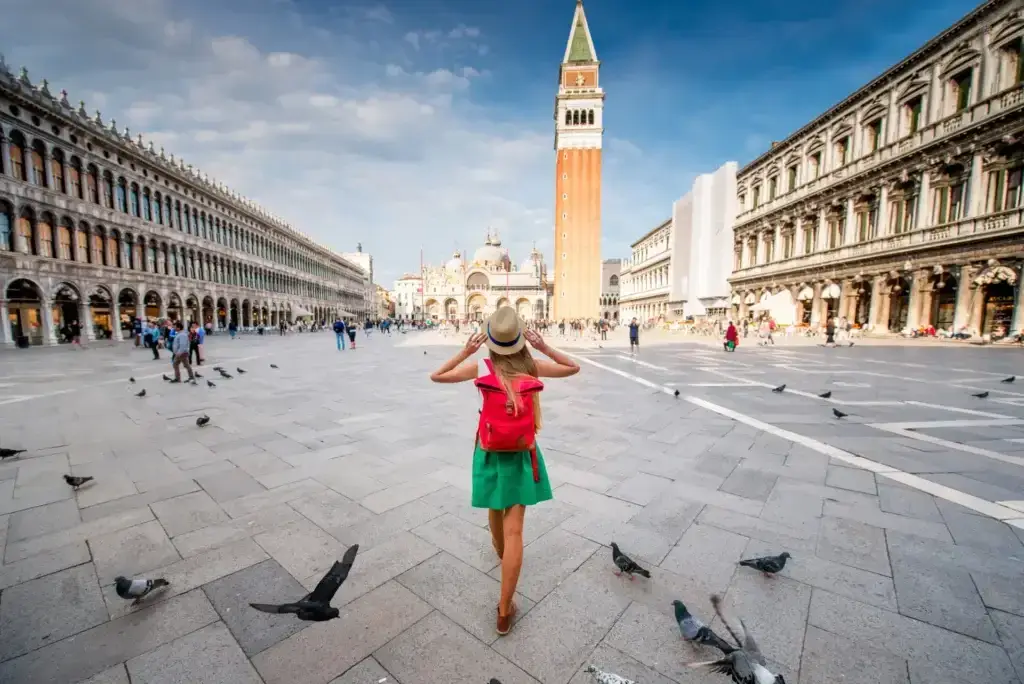 Woman admiring the iconic St. Mark's Square in Venice, Italy, surrounded by pigeons on a sunny day
