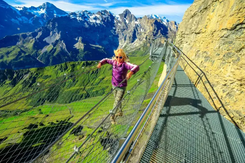 Tourist enjoying the Thrill Walk on Schilthorn, Switzerland with scenic alpine views and mountain peaks in the background