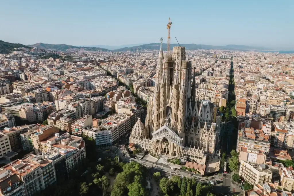 Aerial view of La Sagrada Familia Basilica in Barcelona at sunrise, highlighting its intricate architecture amidst the bustling city landscape.
