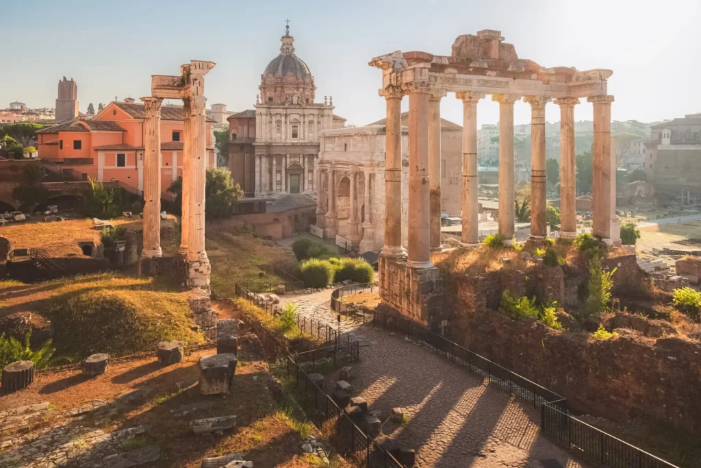 Golden sunrise illuminating the Roman Forum, showcasing ancient columns and ruins with the Basilica of Maxentius in the background, Rome, Italy