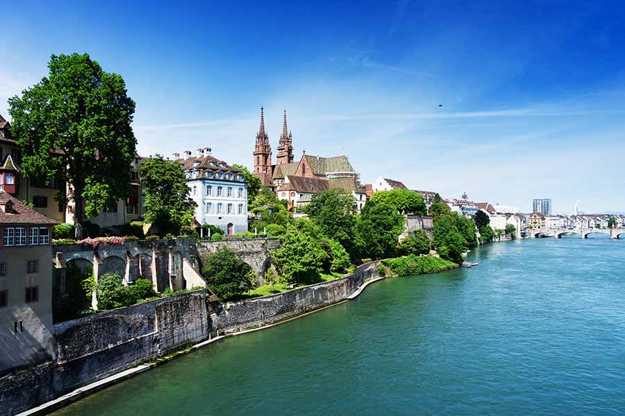 Scenic view of Basel, Switzerland featuring historic architecture and the Rhine River on a sunny day.