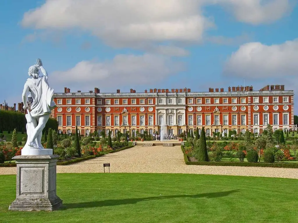Stunning view of Hampton Court Palace with manicured gardens and classical statue in England