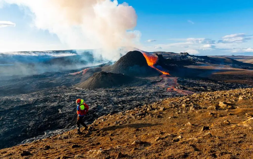 Hiker observing the active Meradalir volcano on the Reykjanes Peninsula in Iceland during a guided tour.