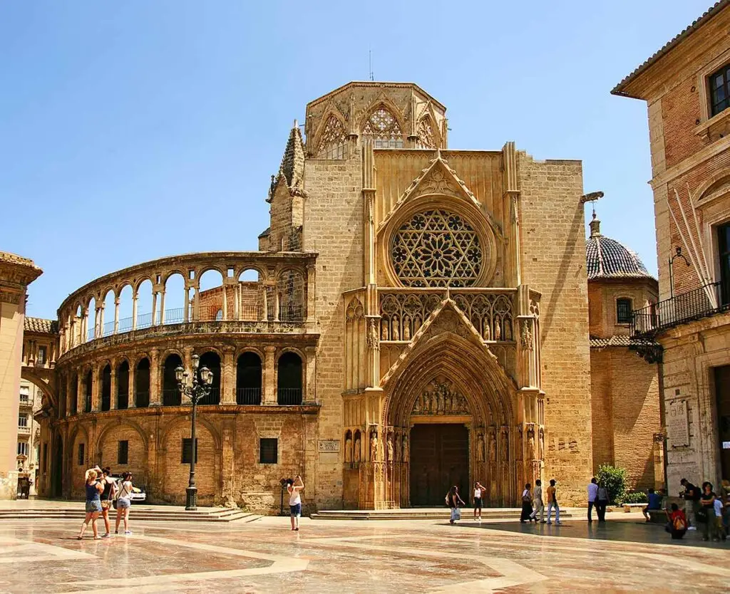 Tourists exploring the striking Gothic architecture of Valencia Cathedral, a historic landmark in Valencia, Spain under sunny skies.
