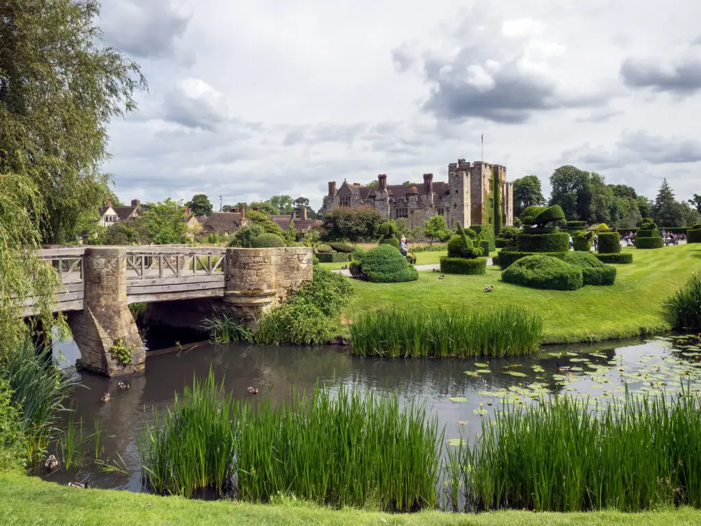 Historic Hever Castle in Kent, England with manicured gardens, stone bridge, and moat on a summer day