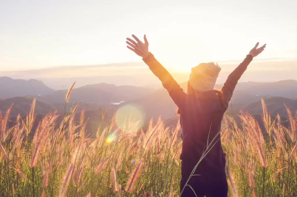 Traveler enjoying sunrise over the Swiss Alps mountains surrounded by alpine grass, Switzerland private tour scenery