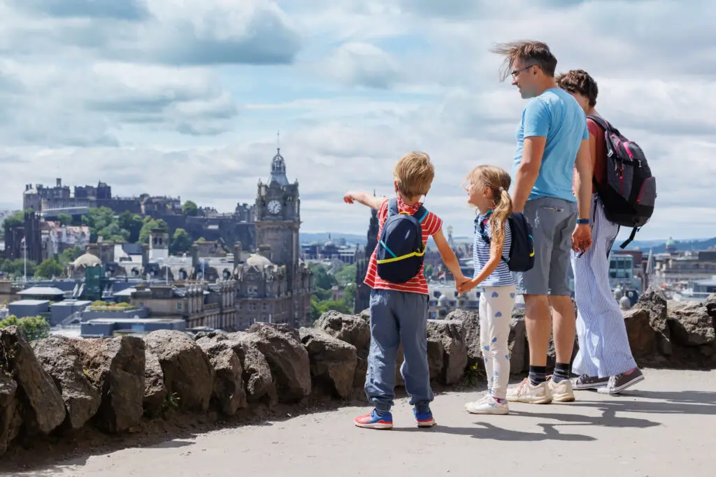 Family with children enjoying panoramic view of Edinburgh city skyline and historic architecture during private tour in Scotland