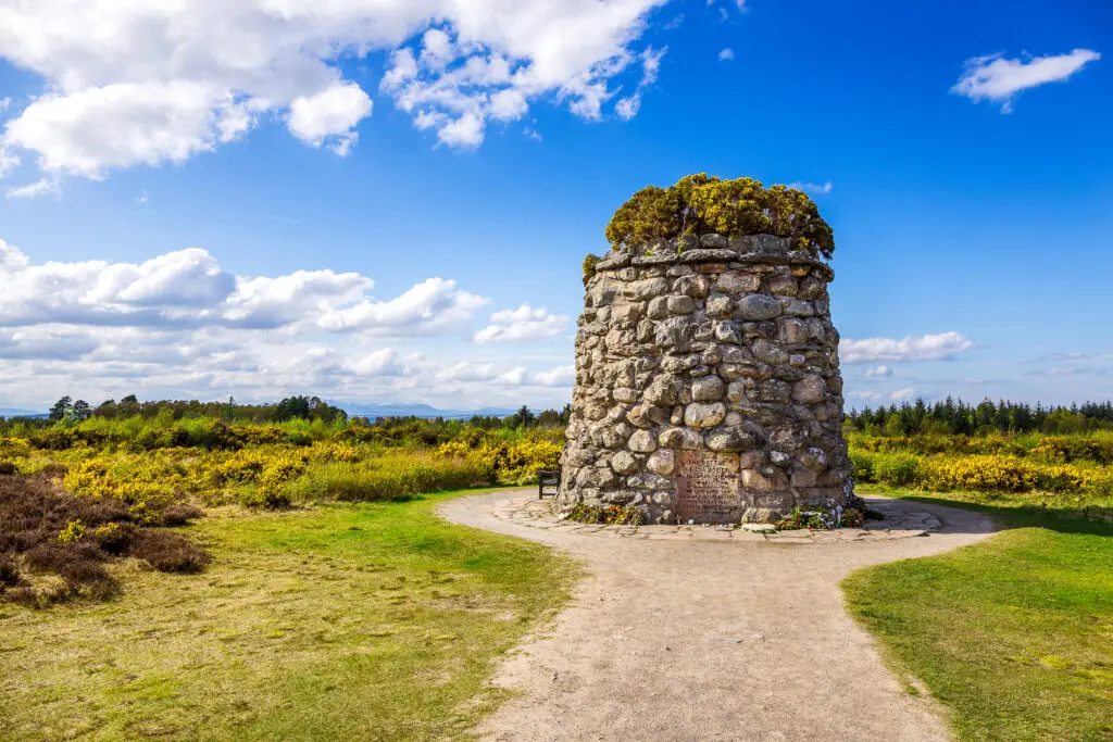 Historic Memorial Cairn at the Battlefield of Culloden in Scotland surrounded by green countryside and blue sky, popular heritage site and tourist attraction in the Scottish Highlands