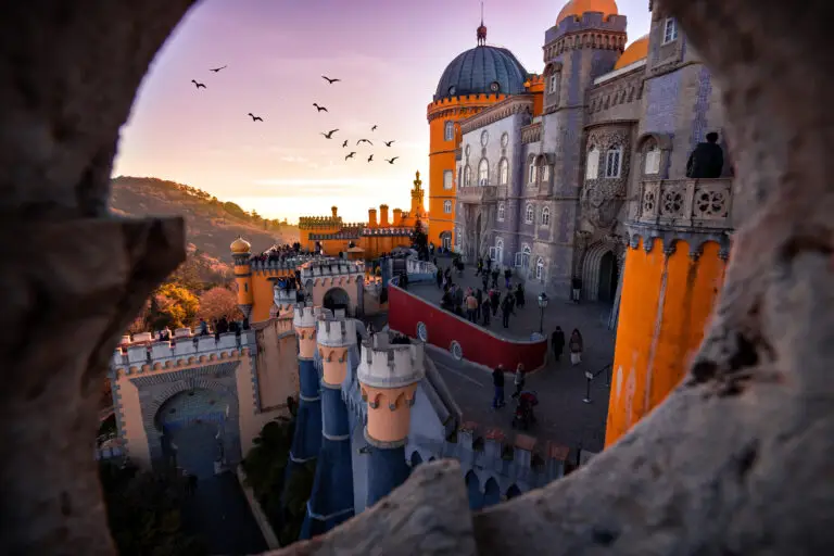 Colorful Pena Palace in Sintra, Portugal at sunset with tourists exploring the historic castle and scenic mountain views