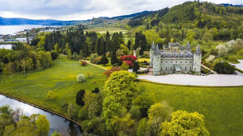Aerial view of Inveraray Castle in Argyll, Scotland surrounded by lush green gardens, trees, and the scenic Scottish Highlands landscape