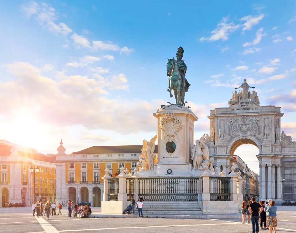 Arco da Rua Augusta and Praça do Comércio at sunset in Lisbon Portugal with tourists exploring the historic city square