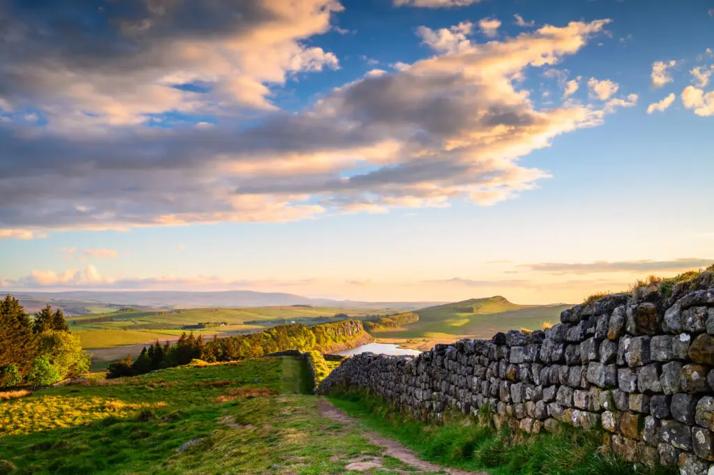 Hadrian’s Wall above Hotbank Crags in Northumberland National Park England UNESCO World Heritage Site with scenic rolling hills walking trails and sunset views along Hadrian’s Wall Path