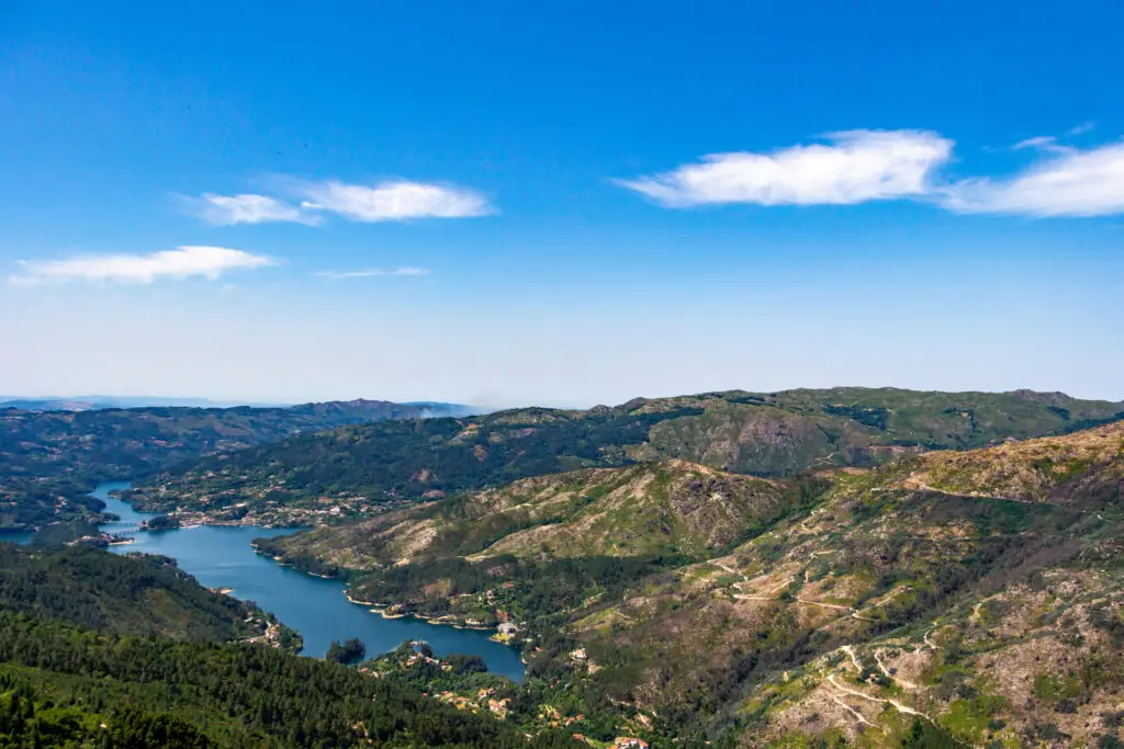 Scenic landscape of Peneda-Gerês National Park in Portugal featuring lush green mountains, winding river, and clear blue sky, a popular destination for nature tours and outdoor adventures in northern Portugal