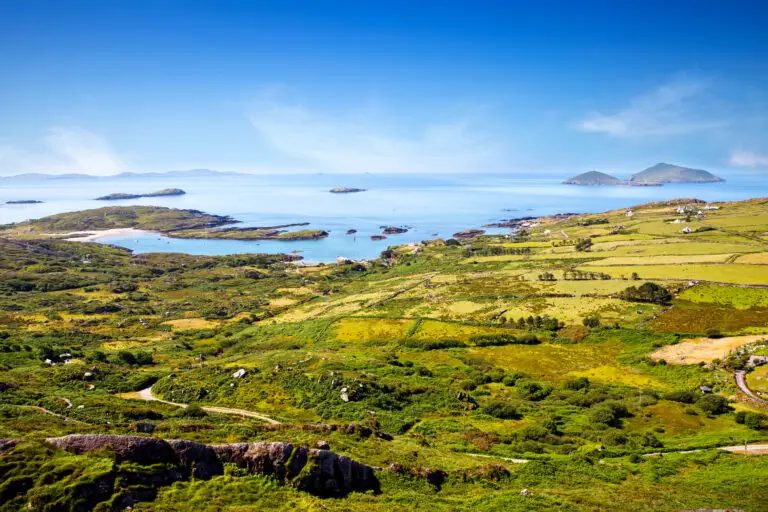 Scenic view of the Ring of Kerry coastline in Ireland with lush green fields, winding roads, and the Atlantic Ocean in the distance, popular destination for Ireland private tours and sightseeing.