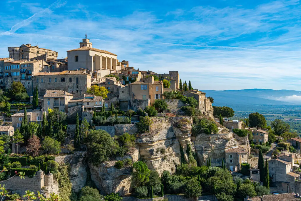Scenic view of Gordes village in Provence France with historic stone houses built on a hill overlooking the Luberon Valley under a bright blue sky