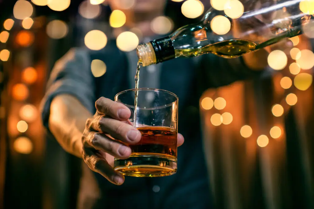 Person pouring Scotch whisky into a glass during an evening tasting experience in Edinburgh, Scotland
