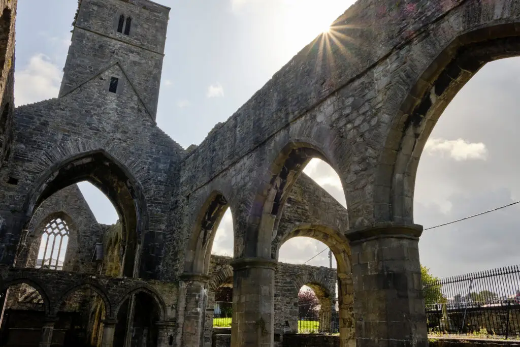 Historic stone ruins and gothic arches of Sligo Abbey in County Sligo, Ireland, illuminated by sunlight, showcasing medieval architecture and a popular heritage site for Irish cultural tours