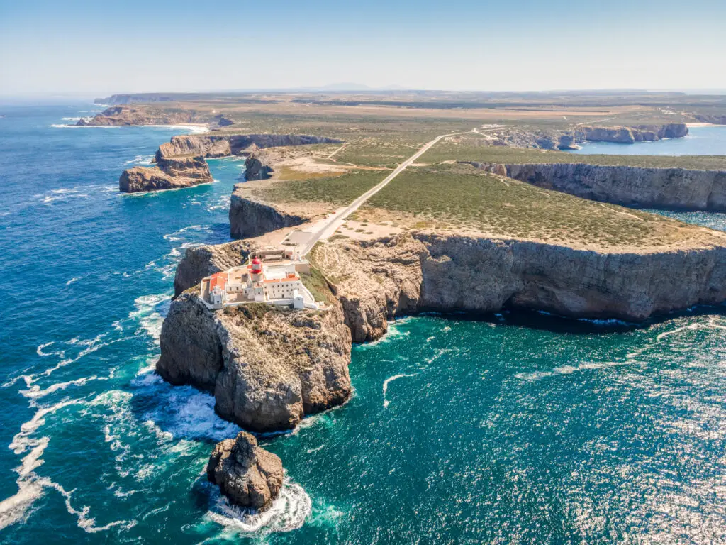 Aerial view of Cape Saint Vincent lighthouse on dramatic cliffs in Algarve, Portugal, overlooking the blue Atlantic Ocean and rugged coastline