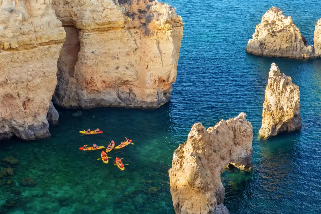 Kayakers exploring the limestone cliffs and turquoise waters of Ponta da Piedade in Lagos, Algarve, Portugal
