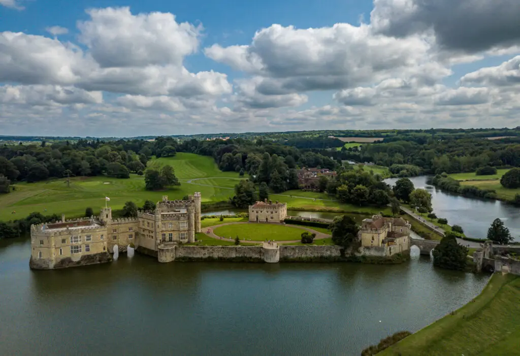 Aerial view of Leeds Castle surrounded by a moat and lush green countryside in Kent, England, a popular historic tourist attraction and day trip destination in the UK
