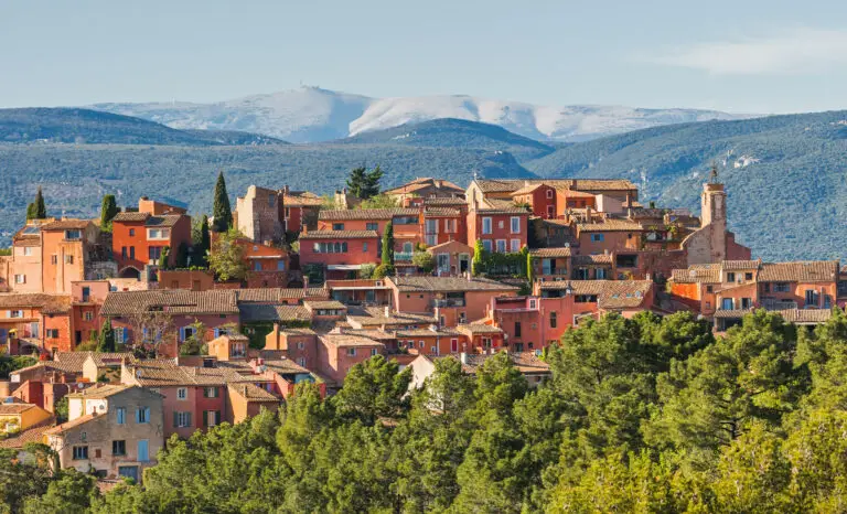 Colorful hilltop village of Roussillon in Provence, France with Mount Ventoux in the background, a popular travel destination for European private tours