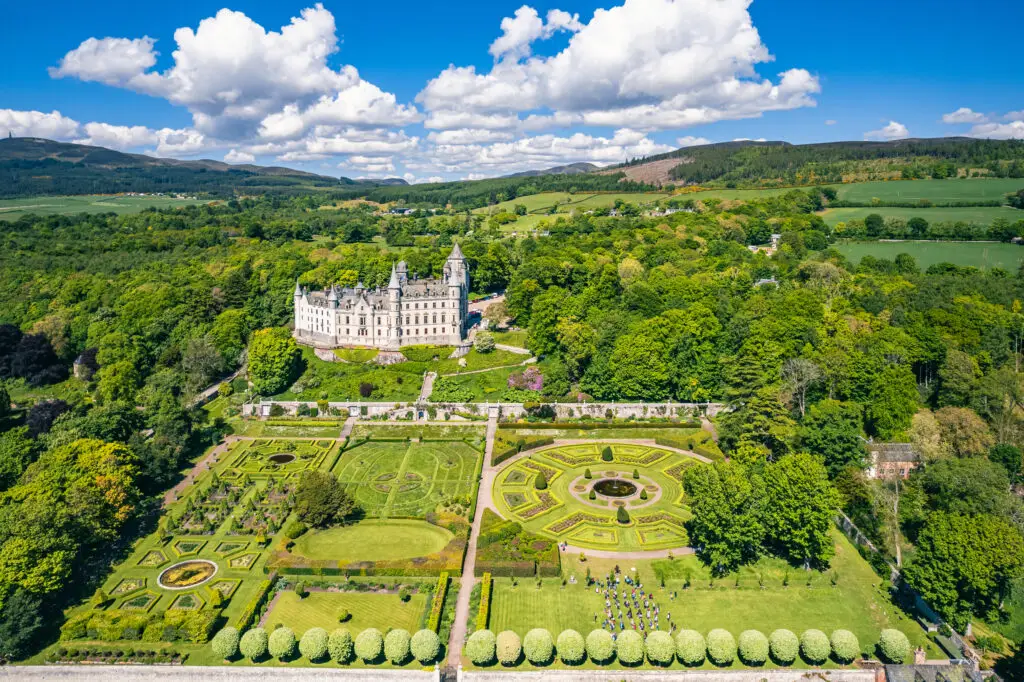 Aerial view of Dunrobin Castle and its formal gardens surrounded by lush greenery along the NC500 route in the Scottish Highlands, Scotland