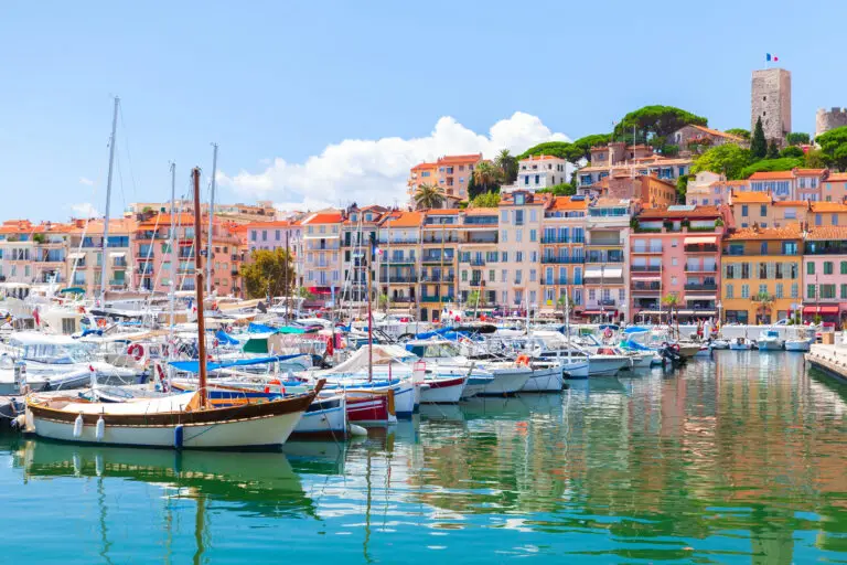 Colorful harbor with yachts and boats in Cannes, France, featuring Mediterranean waterfront buildings and Old Town architecture on the French Riviera