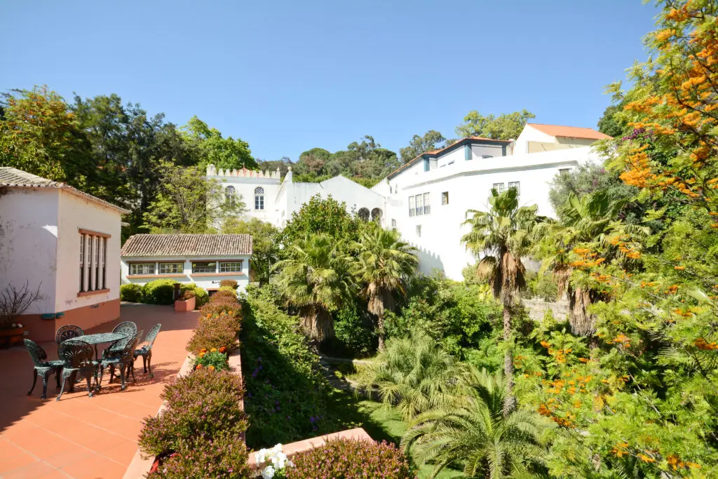 Beautiful view of Caldas de Monchique health resort in Algarve, Portugal with white historic buildings, lush green gardens, palm trees, and sunny Mediterranean atmosphere