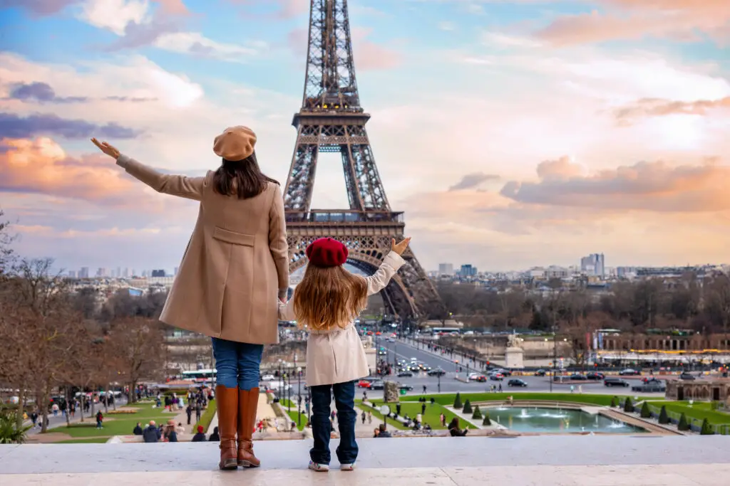 Mother and daughter in stylish coats and berets admiring the Eiffel Tower at sunset in Paris France, popular European travel destination and private tour experience