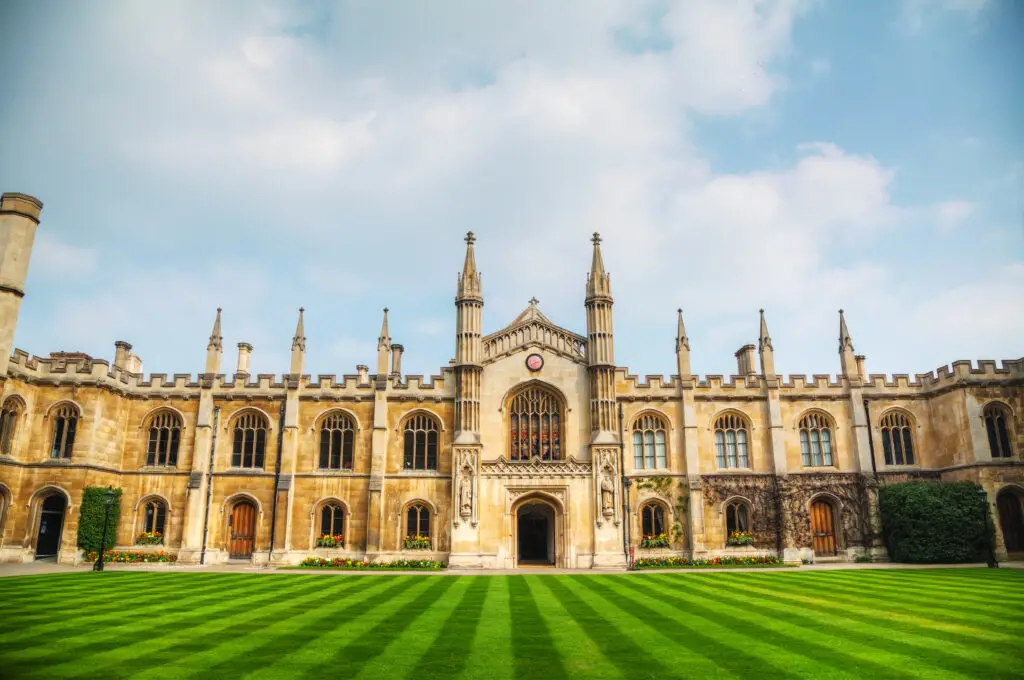 Historic university building with Gothic architecture and manicured lawn in Cambridge, England