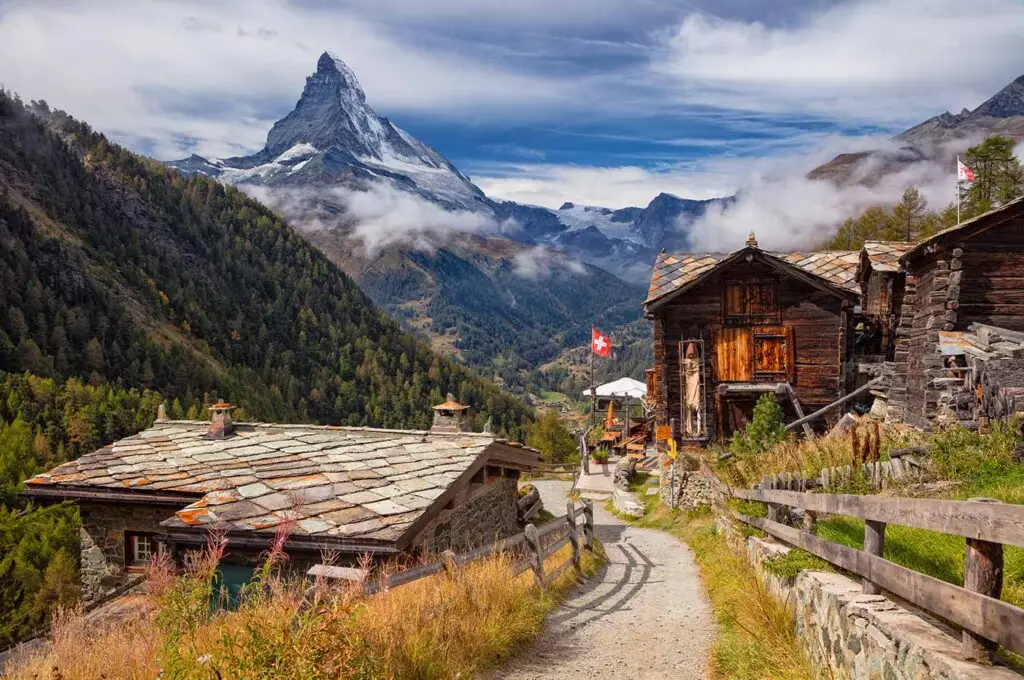 Scenic view of Swiss alpine village near the Matterhorn mountain with traditional wooden chalets and Swiss flag during a 7 day Switzerland tour