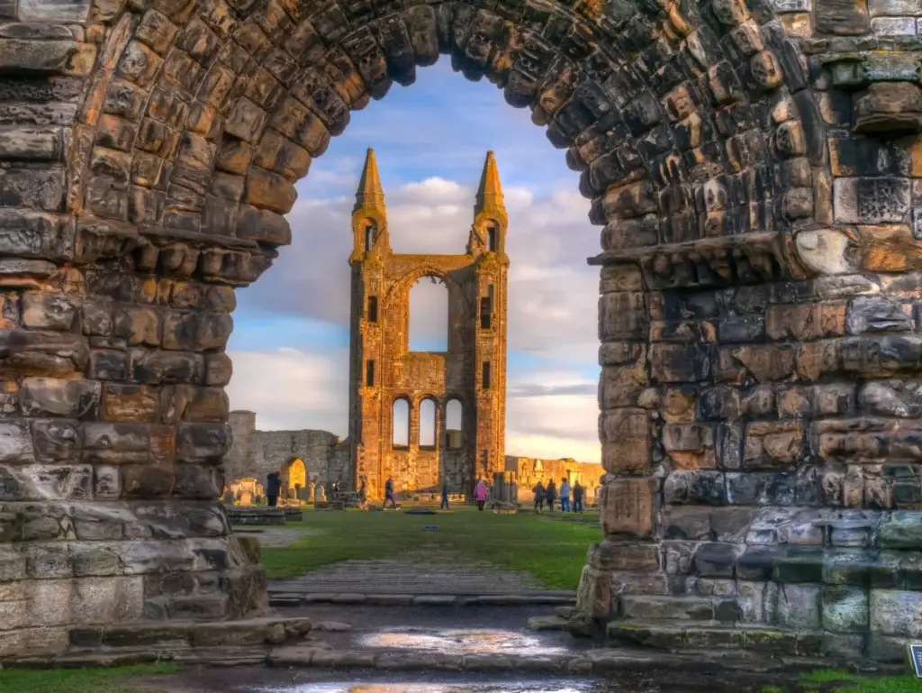 Ruins of St Andrews Cathedral in Scotland viewed through a stone archway, showcasing historic architecture and popular tourist attraction at sunset