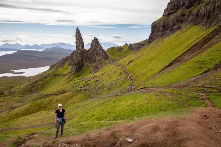 Tourist hiking at the Old Man of Storr on the Isle of Skye, Scotland, surrounded by dramatic rock formations and lush green hills