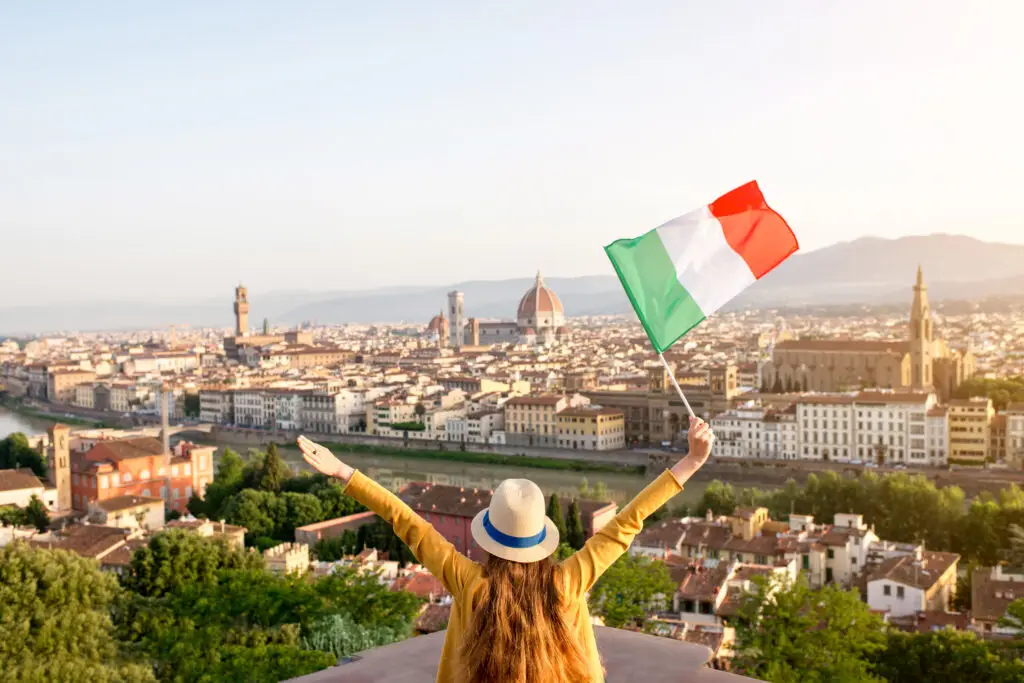 Tourist overlooking Florence, Italy skyline with the Duomo and waving Italian flag during a private European tour