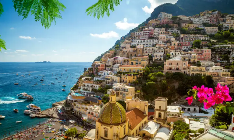 Scenic view of Positano, Italy with colorful cliffside houses overlooking the Amalfi Coast and boats in the turquoise sea, popular destination for European private tours