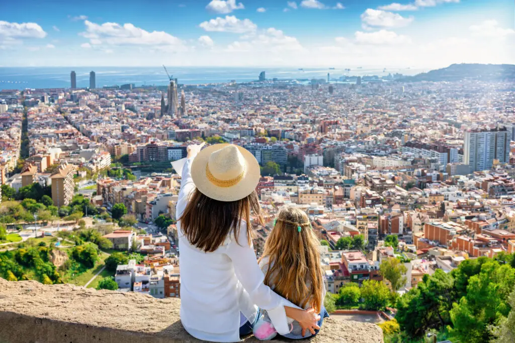 Mother and daughter enjoying panoramic view of Barcelona, Spain with famous city landmarks and Mediterranean Sea in the background