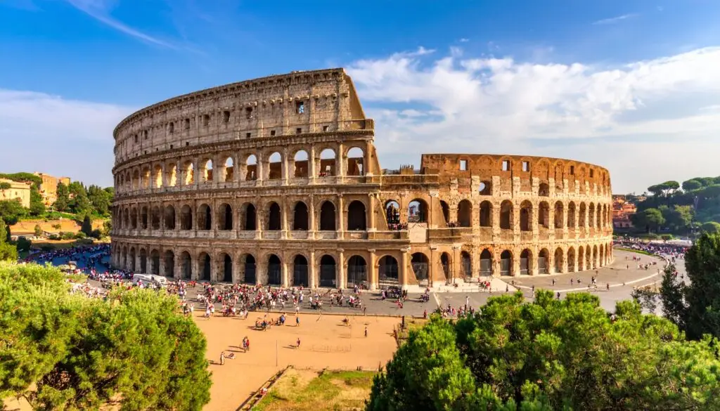 Colosseum in Rome Italy with tourists exploring the ancient Roman amphitheater under a bright blue sky