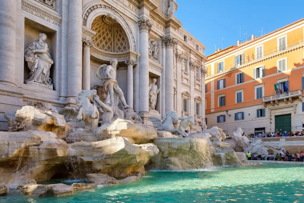 Trevi Fountain in Rome Italy with baroque sculptures and turquoise water surrounded by historic buildings and tourists enjoying the famous landmark