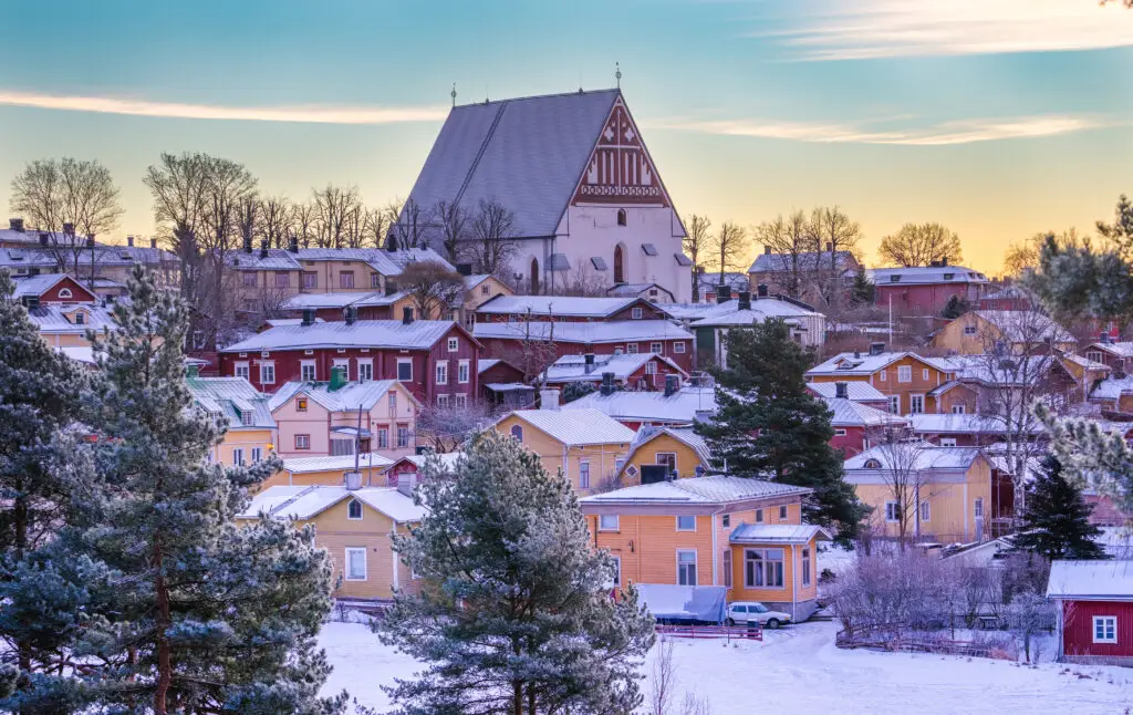 Colorful wooden houses and the historic Porvoo Cathedral in Porvoo Old Town, Finland, during winter at sunset