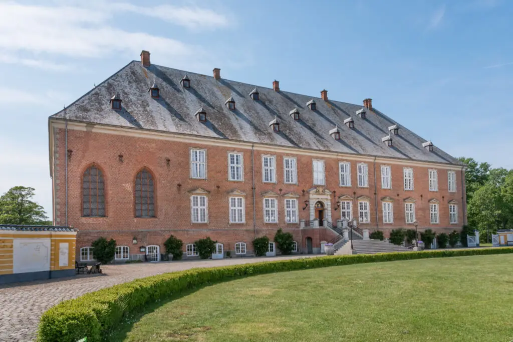 Valdemar Castle in Denmark with its historic red-brick architecture, large windows, and manicured gardens on a sunny day, popular tourist attraction on Tåsinge Island