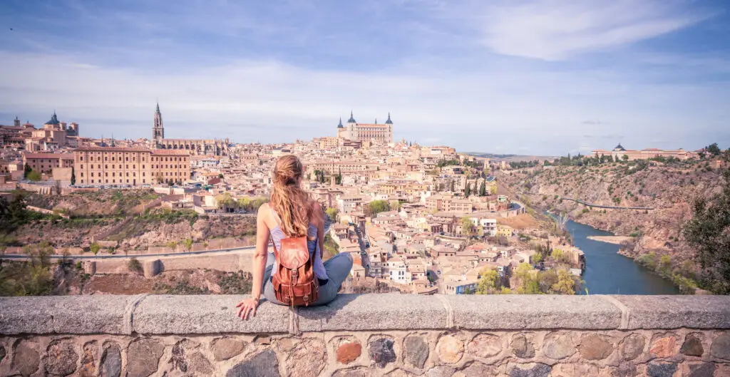 Tourist admiring panoramic view of historic Toledo, Spain with Alcázar and Tagus River in the background