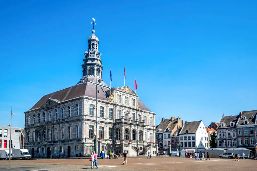 Maastricht Town Hall at Markt Square in the Netherlands with tourists exploring the historic city center on a sunny day